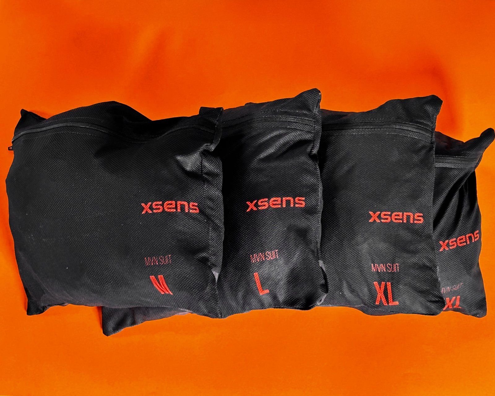 Combinaisons de motion capture Xsens dans leurs housses, sur fond orange
