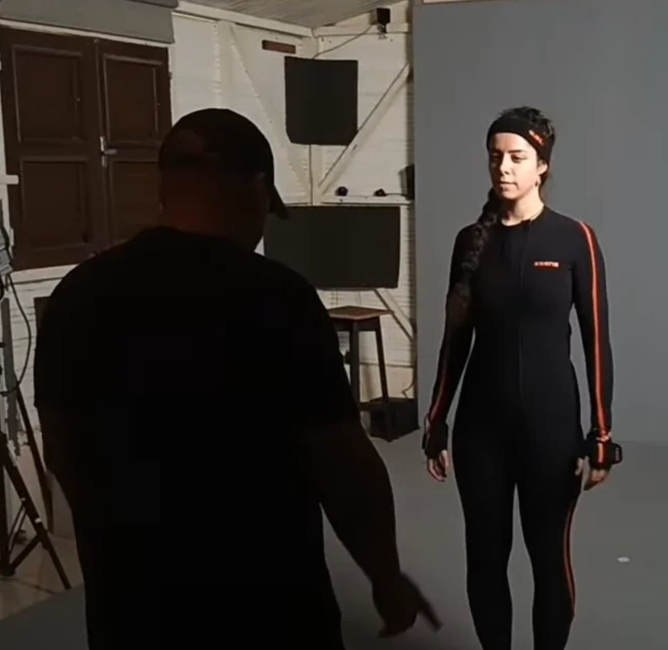 Un réalisateur dirige une performeuse en combinaison de motion capture